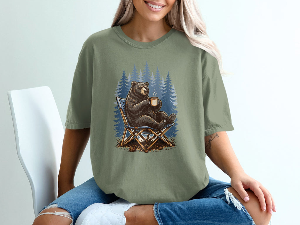 Bear sitting in a chair with coffee in front of pine trees.