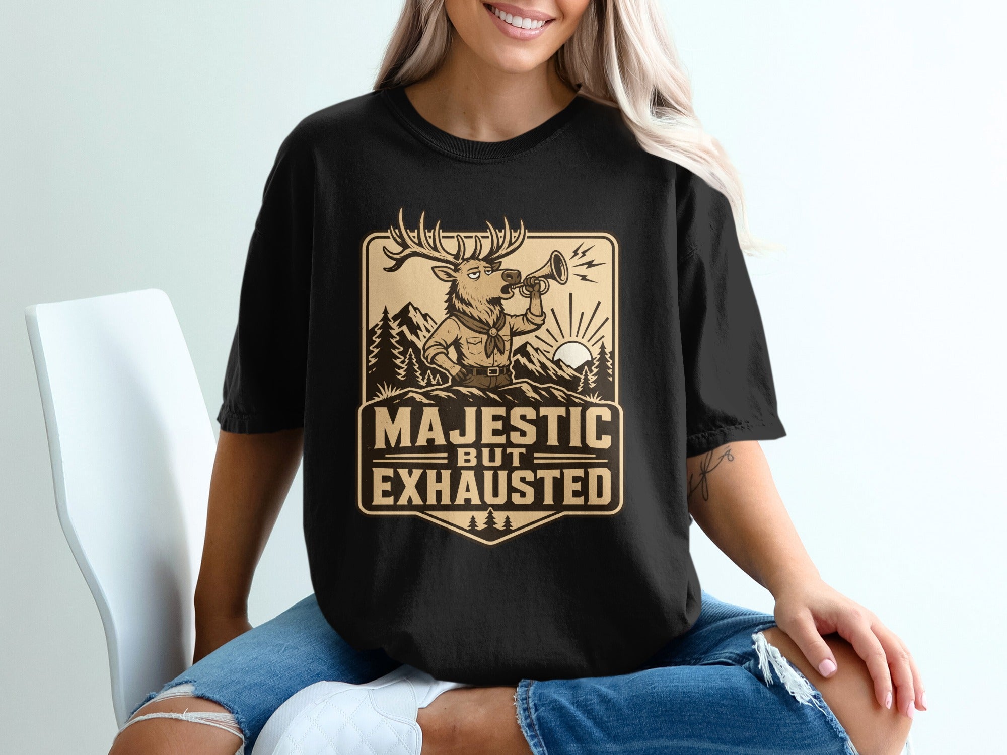 Black t-shirt with a deer blowing a horn and text "Majestic But Exhausted".
