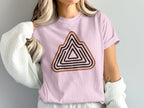 Pink t-shirt with layered mountain graphic in brown and black stripes.