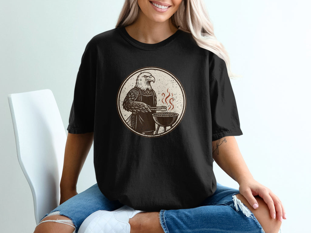 Eagle in apron grilling on a BBQ, vintage illustration on black t-shirt.