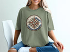 Green t-shirt with a vintage compass design featuring mountains and pine trees.