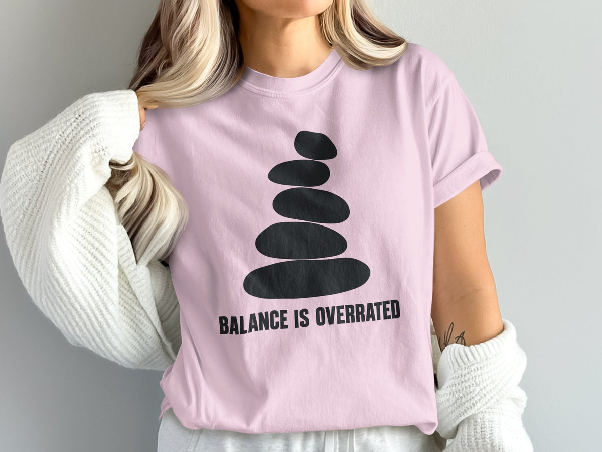 Pink t-shirt with black stacked stones graphic and "BALANCE IS OVERRATED" text.