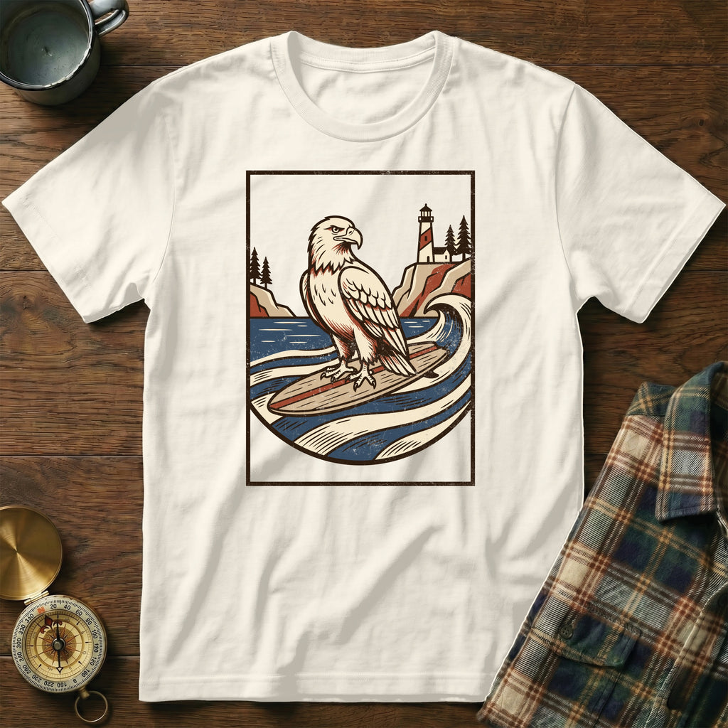 White t-shirt with a graphic of an eagle surfing, lighthouse, and waves.