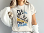A cream-colored t-shirt with a graphic of a fainting goat sliding down a hill, accompanied by the text It's all downhill from here.