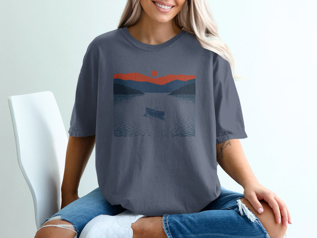 Canoe on a lake at sunset with mountains, graphic print on t-shirt.