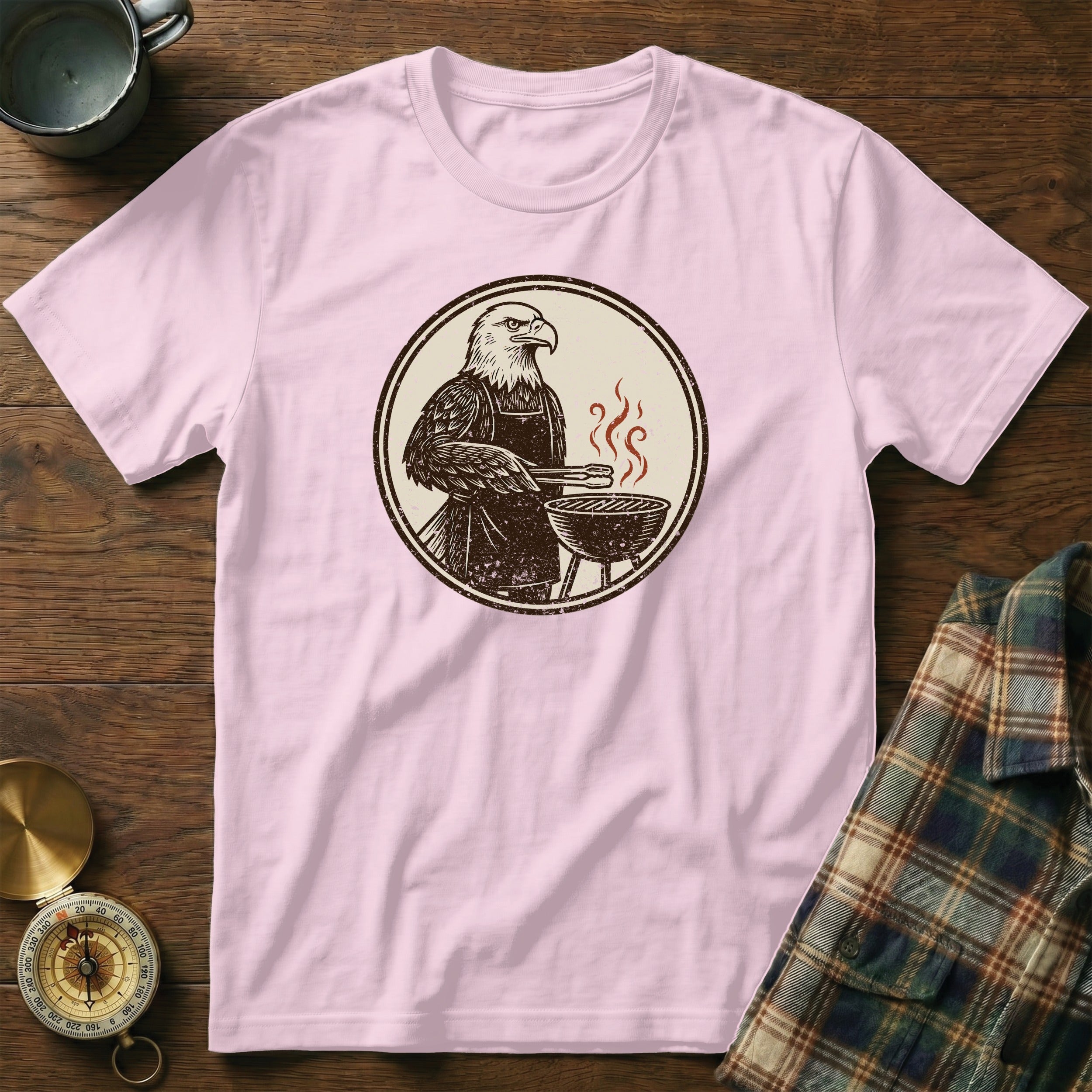 Eagle grilling at a barbecue, printed on a pink t-shirt.