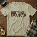 Light tan t-shirt with "LIBERTY LOOKS GOOD ON YOU" text and mountain graphic.