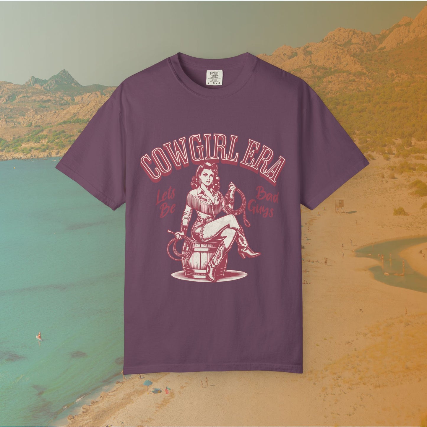 Cowgirl Era pinup T-shirt with a vintage-style illustration of a sassy cowgirl sitting on a barrel holding a lasso. The graphic includes the text "COWGIRL ERA" and "Lets Be Bad Guys.