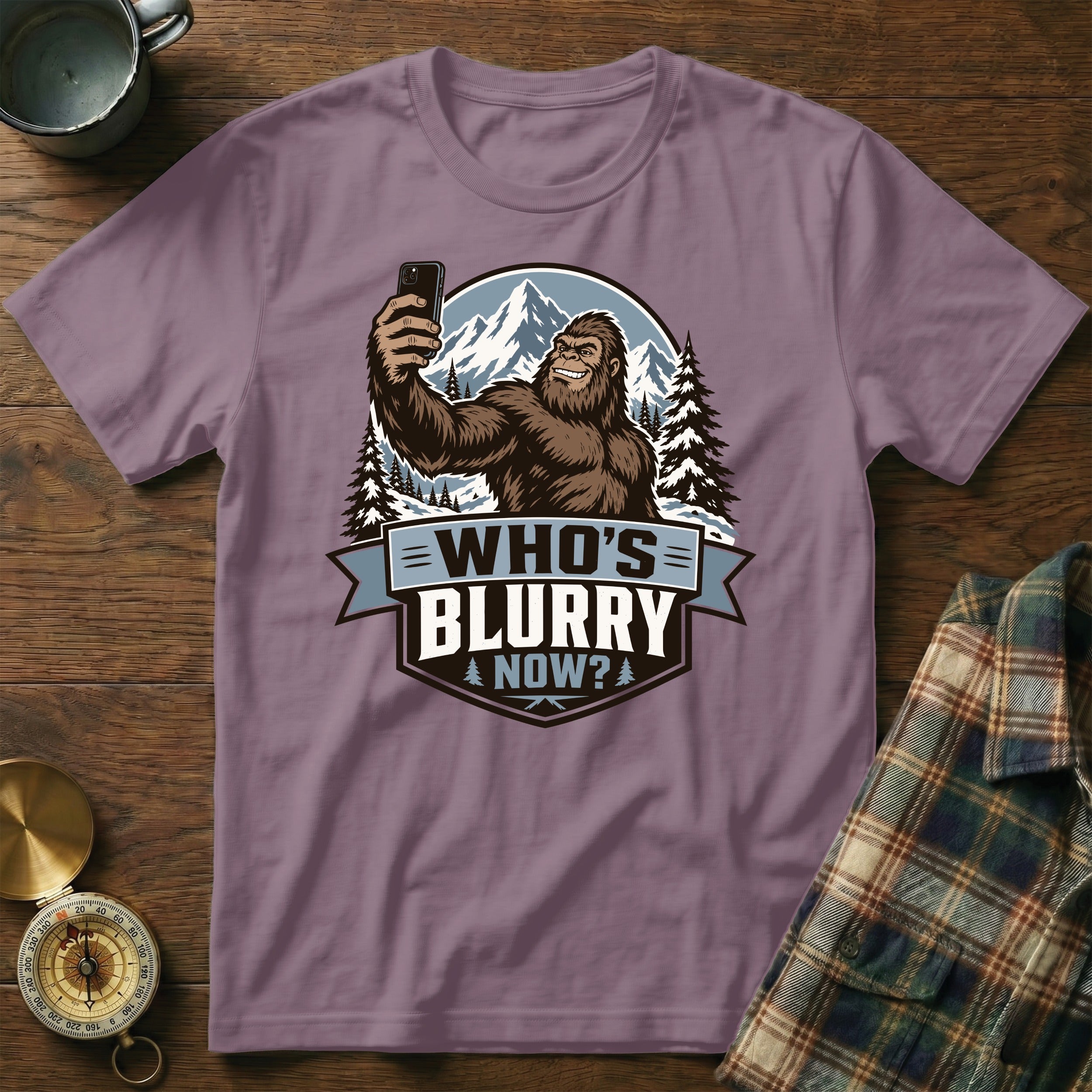 Bigfoot taking a selfie in snowy mountains with text "Who's Blurry Now?".
