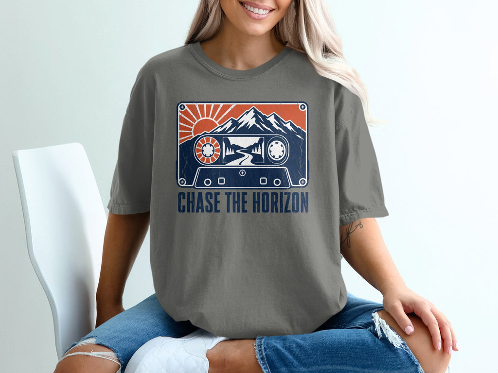T-shirt graphic featuring a cassette tape with mountains, sun, and trees. "CHASE THE HORIZON" text.