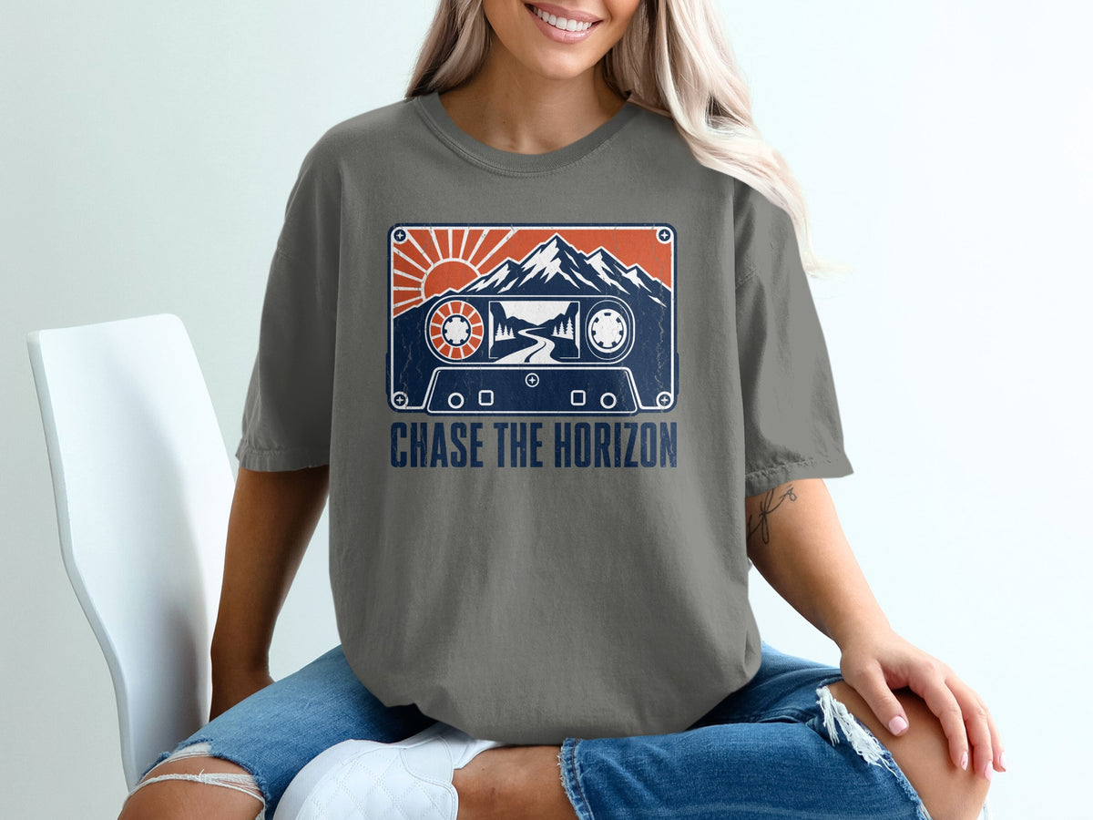 T-shirt graphic featuring a cassette tape with mountains, sun, and trees. "CHASE THE HORIZON" text.