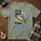 Sage green t-shirt with a mountain goat sliding down a hill and the text It's All Downhill From Here.