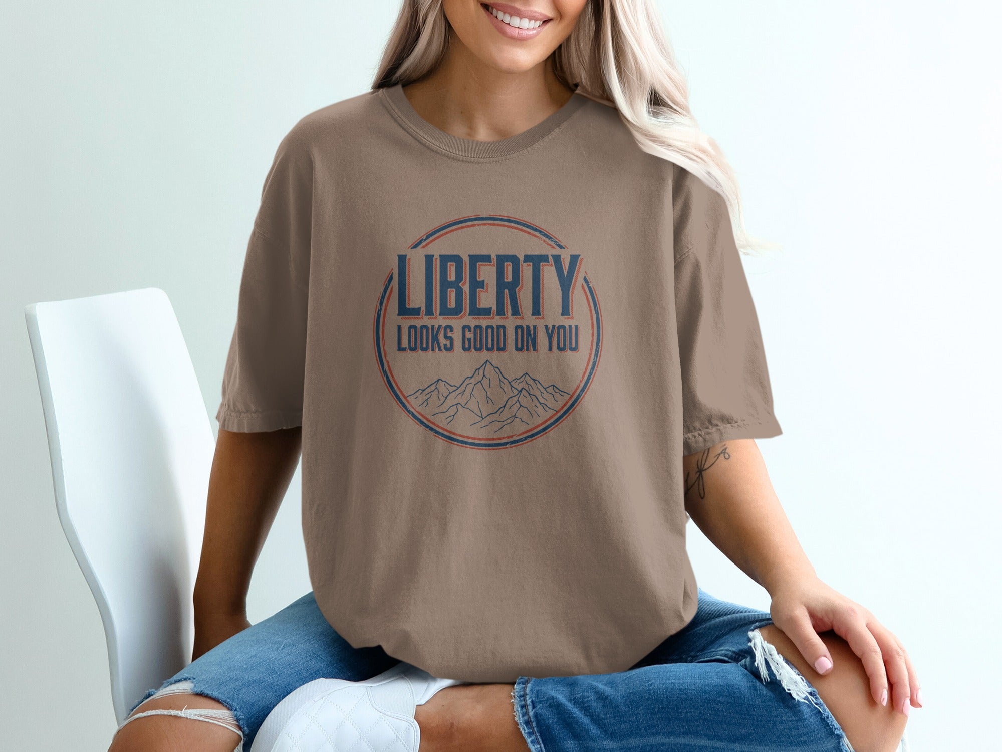 Brown t-shirt with "LIBERTY LOOKS GOOD ON YOU" graphic and mountain illustration.