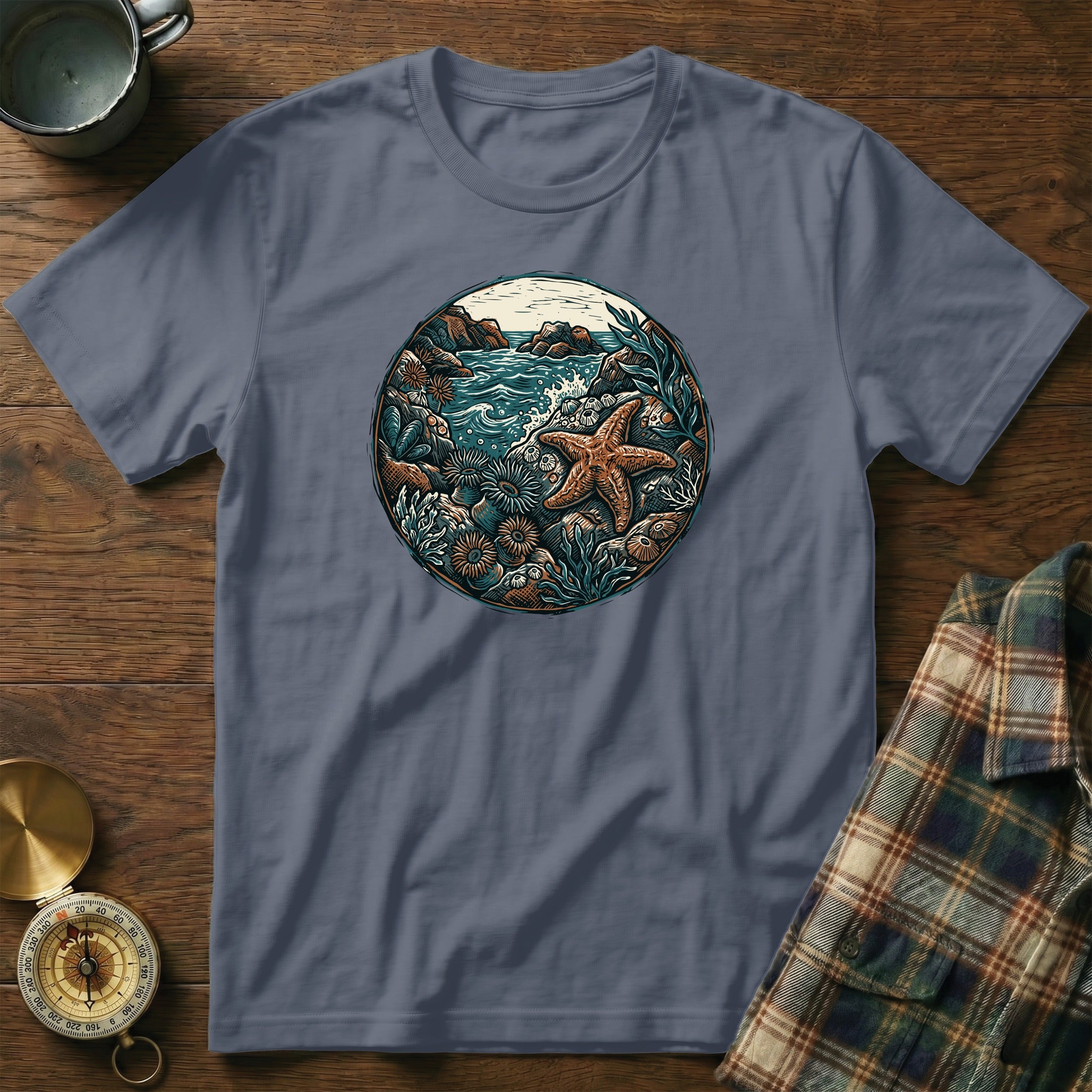 Circular graphic of a starfish and ocean life printed on a slate blue t-shirt.