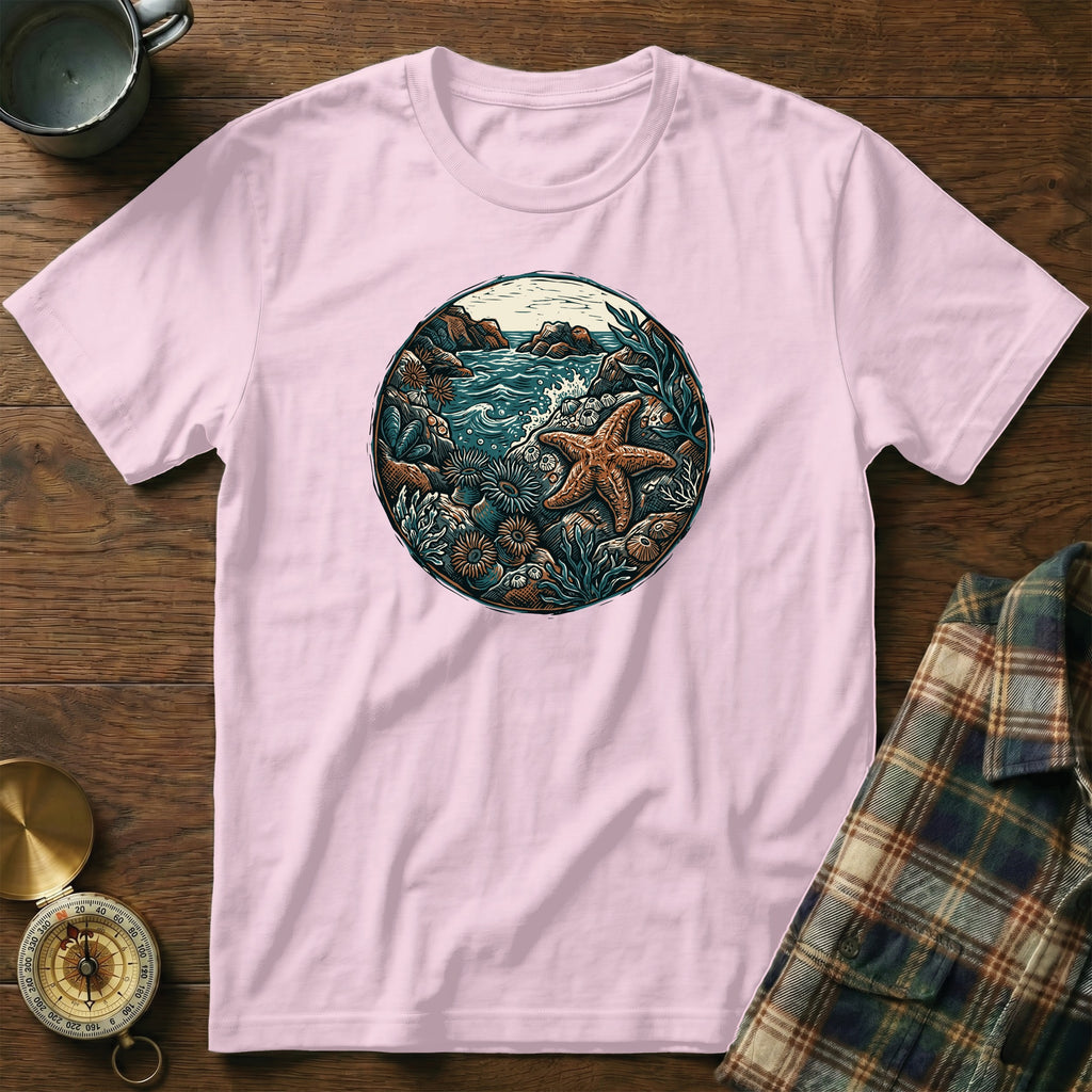 Pink t-shirt featuring circular beach scene with starfish and seashells.