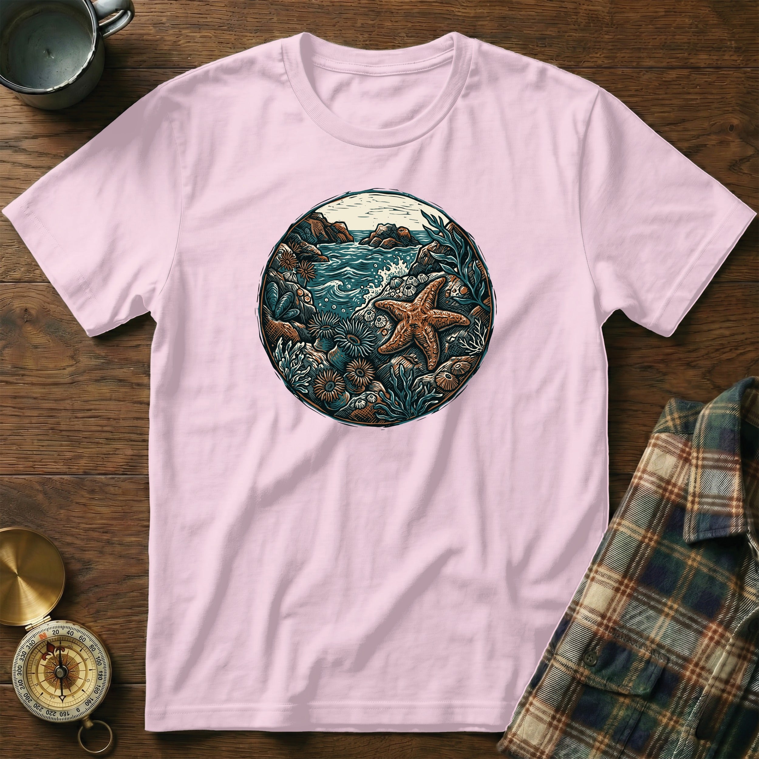 Pink t-shirt featuring circular beach scene with starfish and seashells.