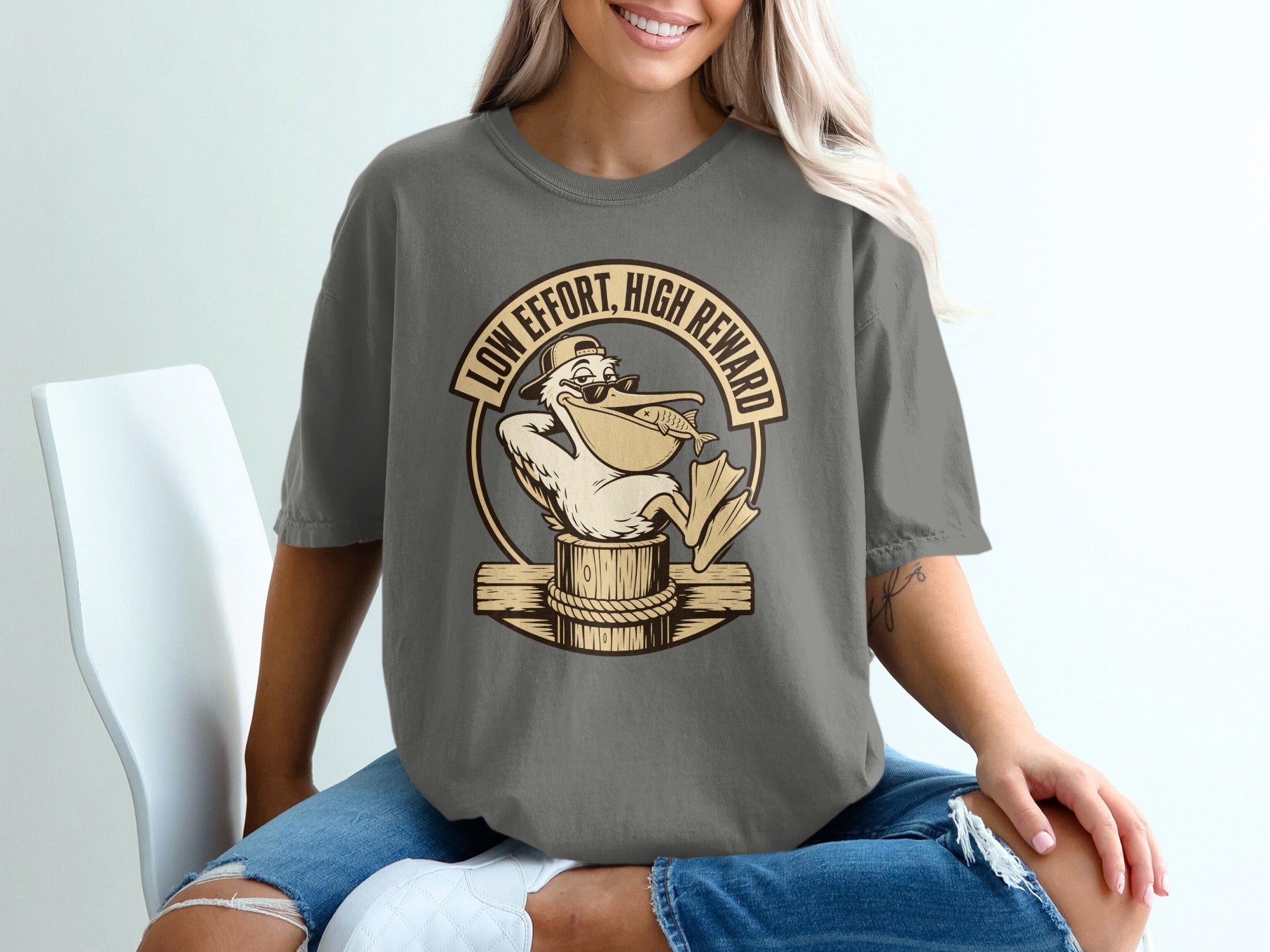 T-shirt graphic of a pelican with sunglasses and a fish, with text "LOW EFFORT, HIGH REWARD".