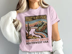 Pink t-shirt with desert mountains graphic and text "Desert to Mountains Adventure Awaits Southwest USA".