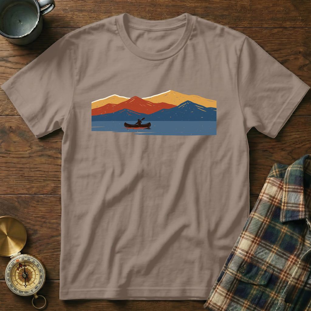 Brown t-shirt with a graphic of a canoeist on a lake with mountains.