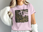 Bigfoot standing on a rocky cliff overlooking a rough sea.