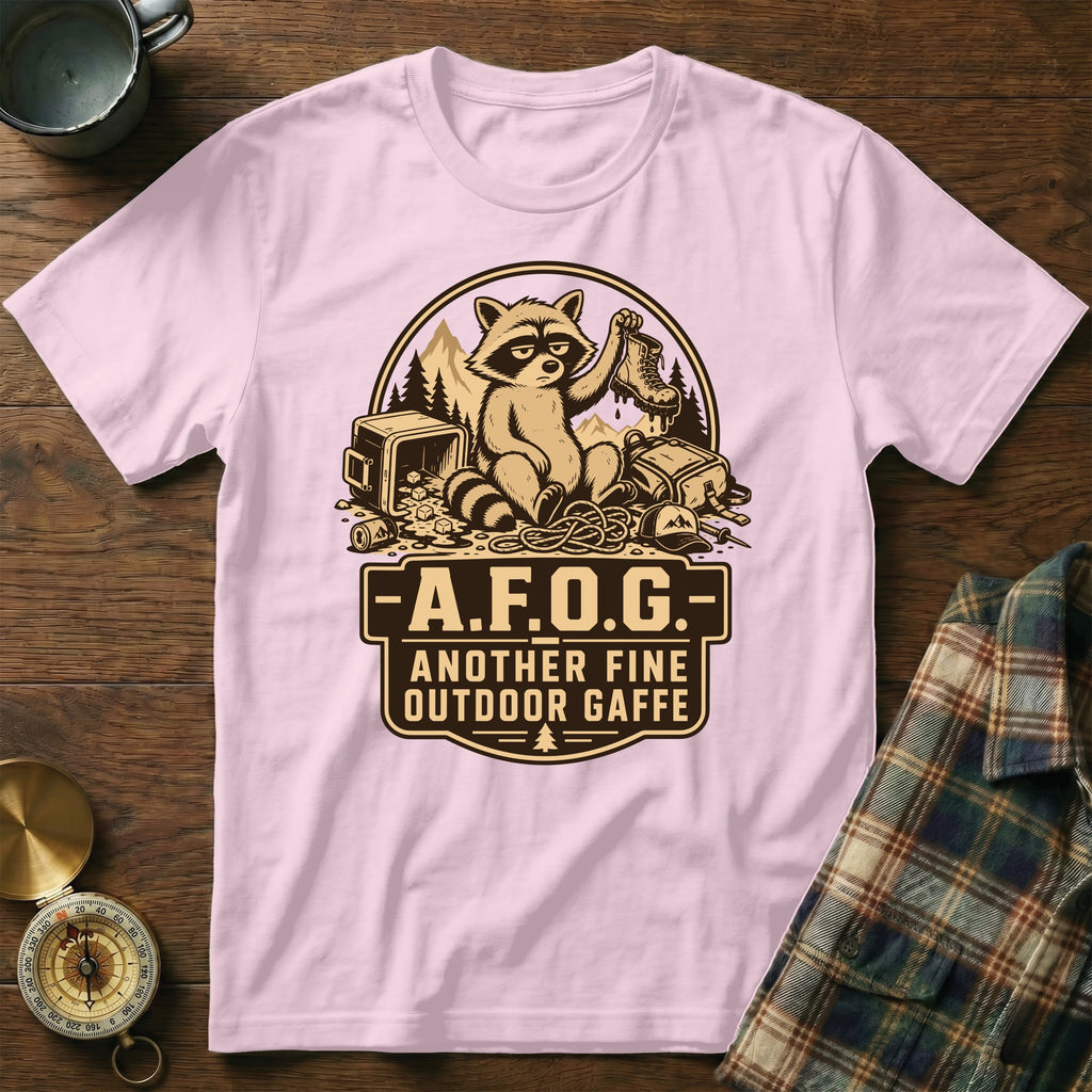 Light pink t-shirt with a graphic of a raccoon on camping gear and the text "A.F.O.G. Another Fine Outdoor Gaffe".