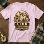 Light pink t-shirt with a graphic of a raccoon on camping gear and the text "A.F.O.G. Another Fine Outdoor Gaffe".