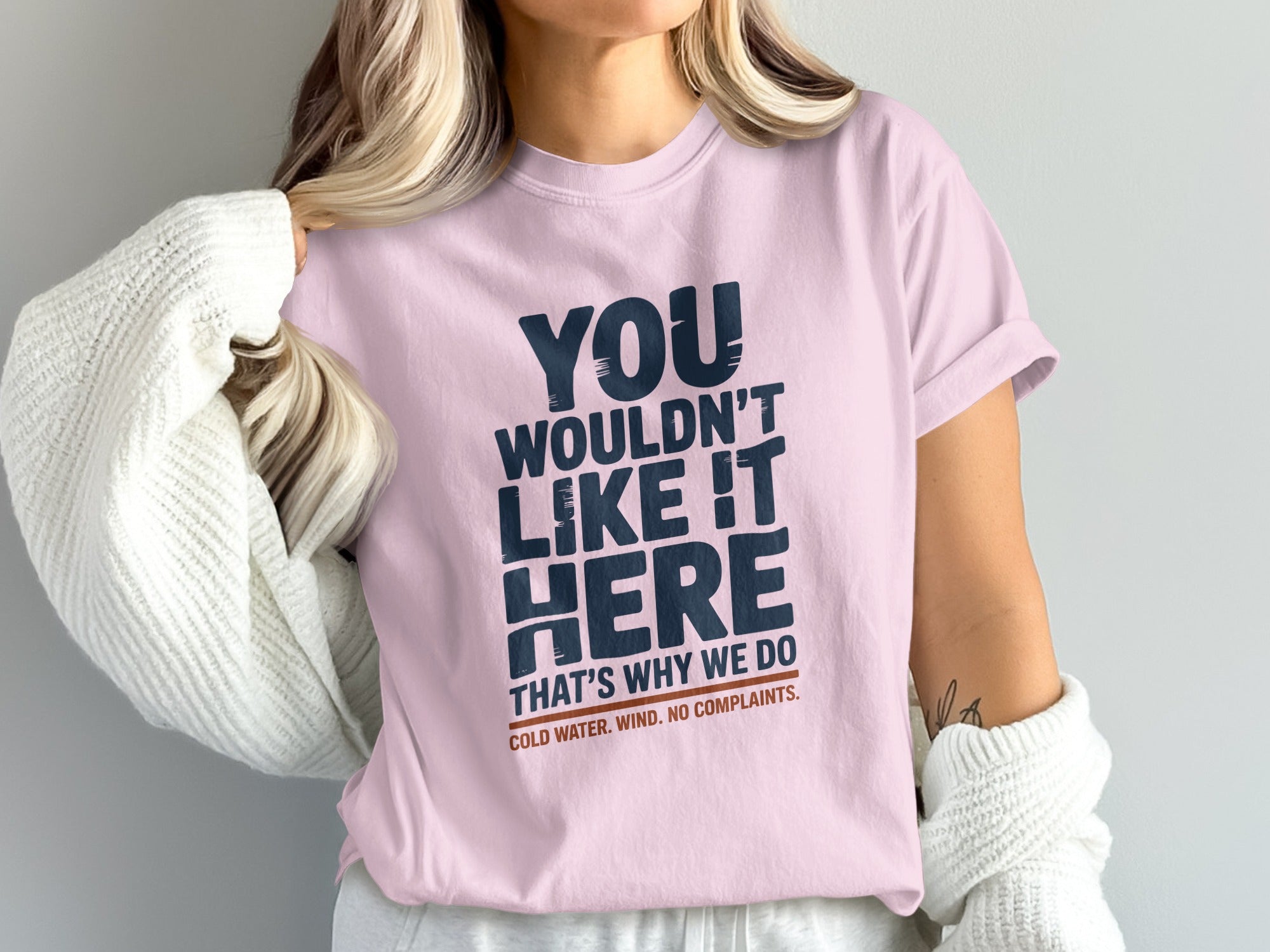 Pink t-shirt with text "You wouldn't like it here. That's why we do cold water. Wind. No complaints."