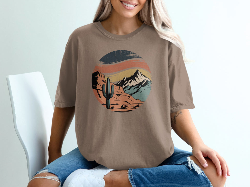 Brown t-shirt with desert mountain landscape graphic featuring a cactus and tent.