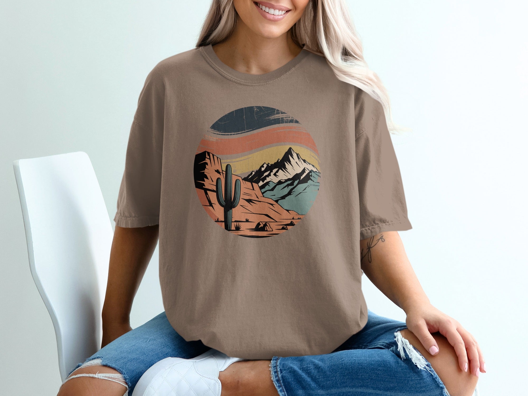 Brown t-shirt with desert mountain landscape graphic featuring a cactus and tent.
