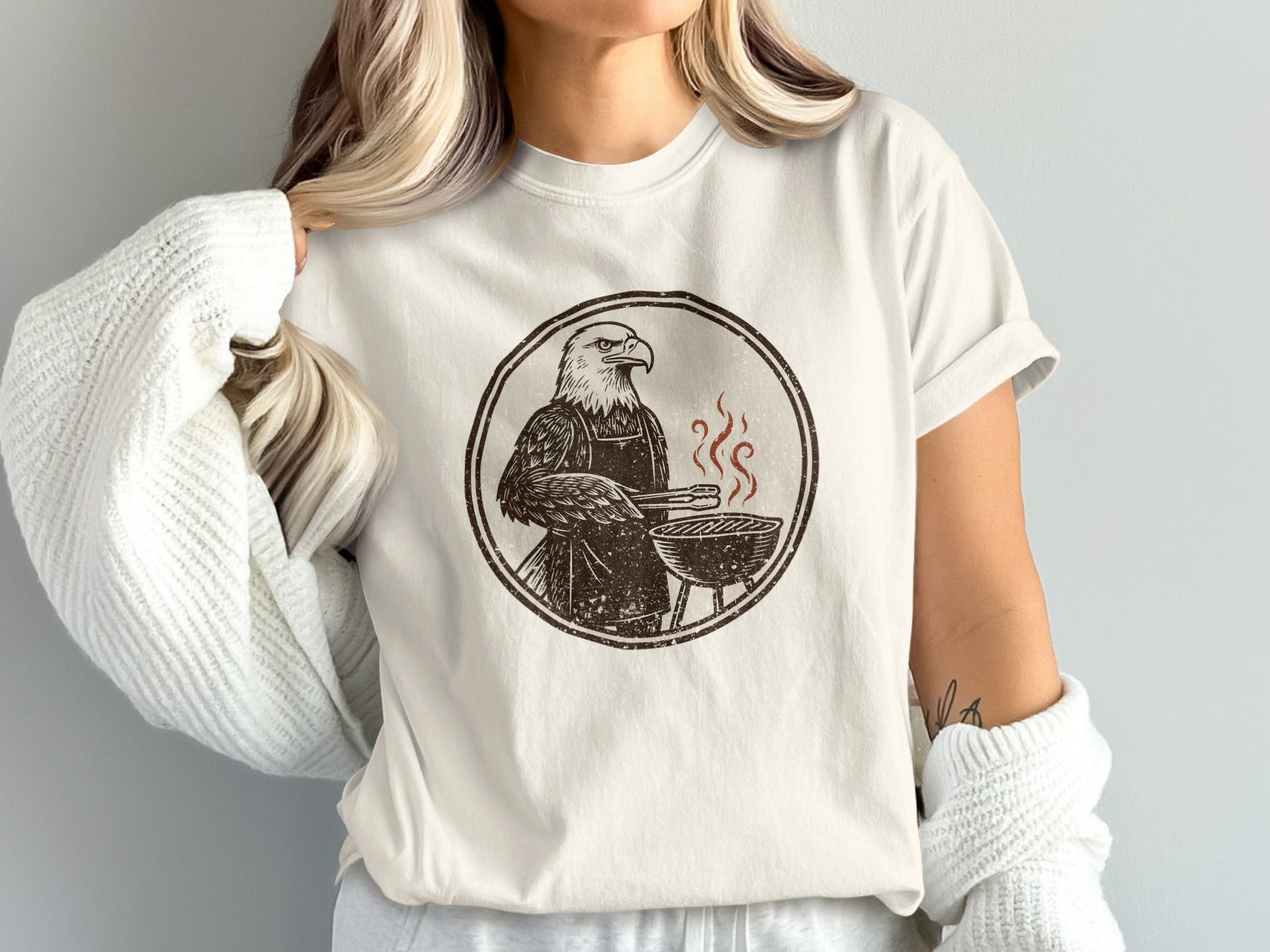 T-shirt graphic of an eagle wearing an apron at a grill.