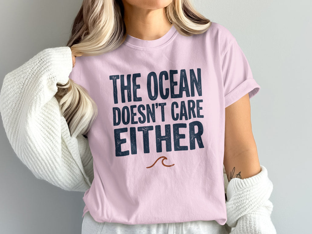 Pink t-shirt with "THE OCEAN DOESN'T CARE EITHER" and wave graphic.