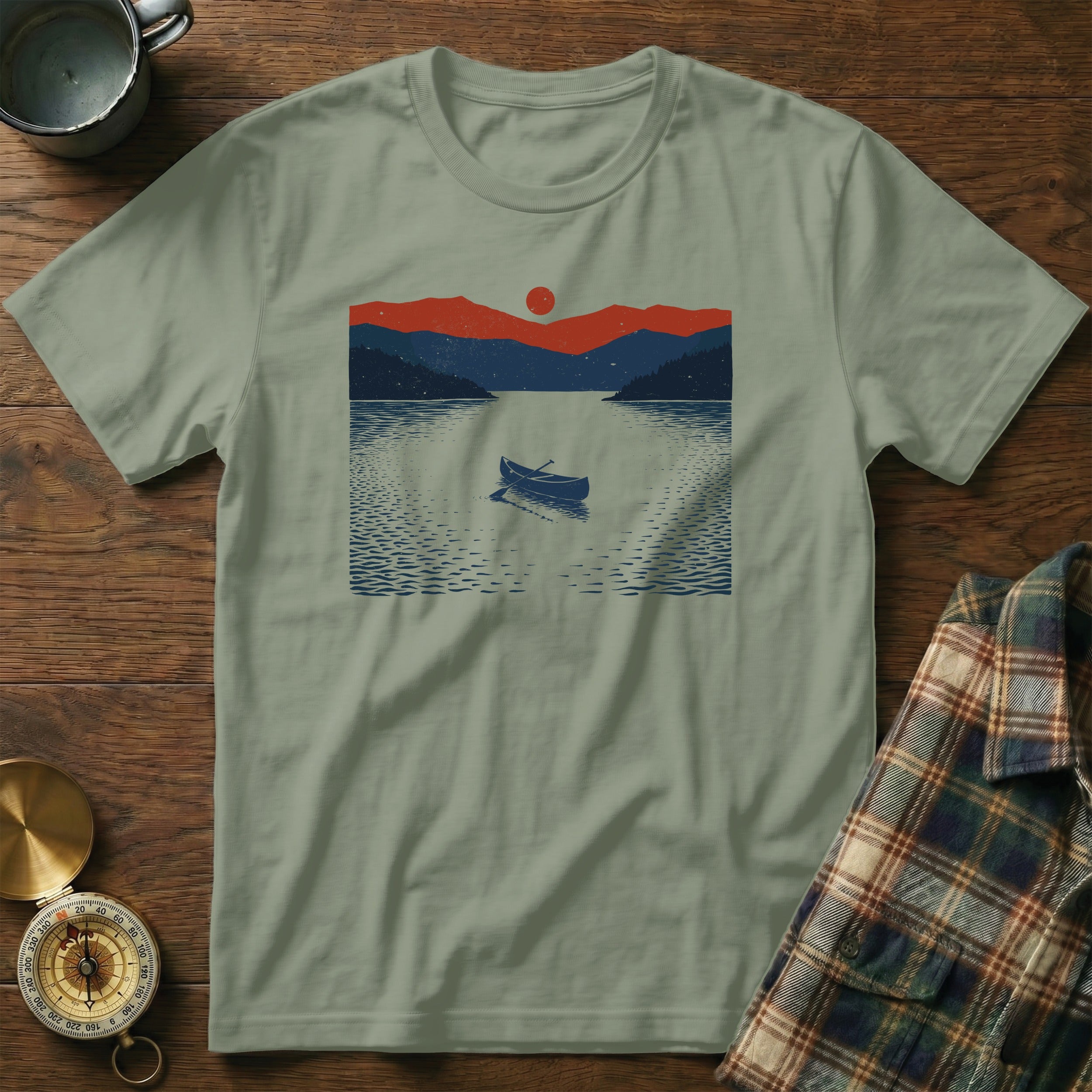 Light green t-shirt with a graphic of a canoe on a lake at sunset.
