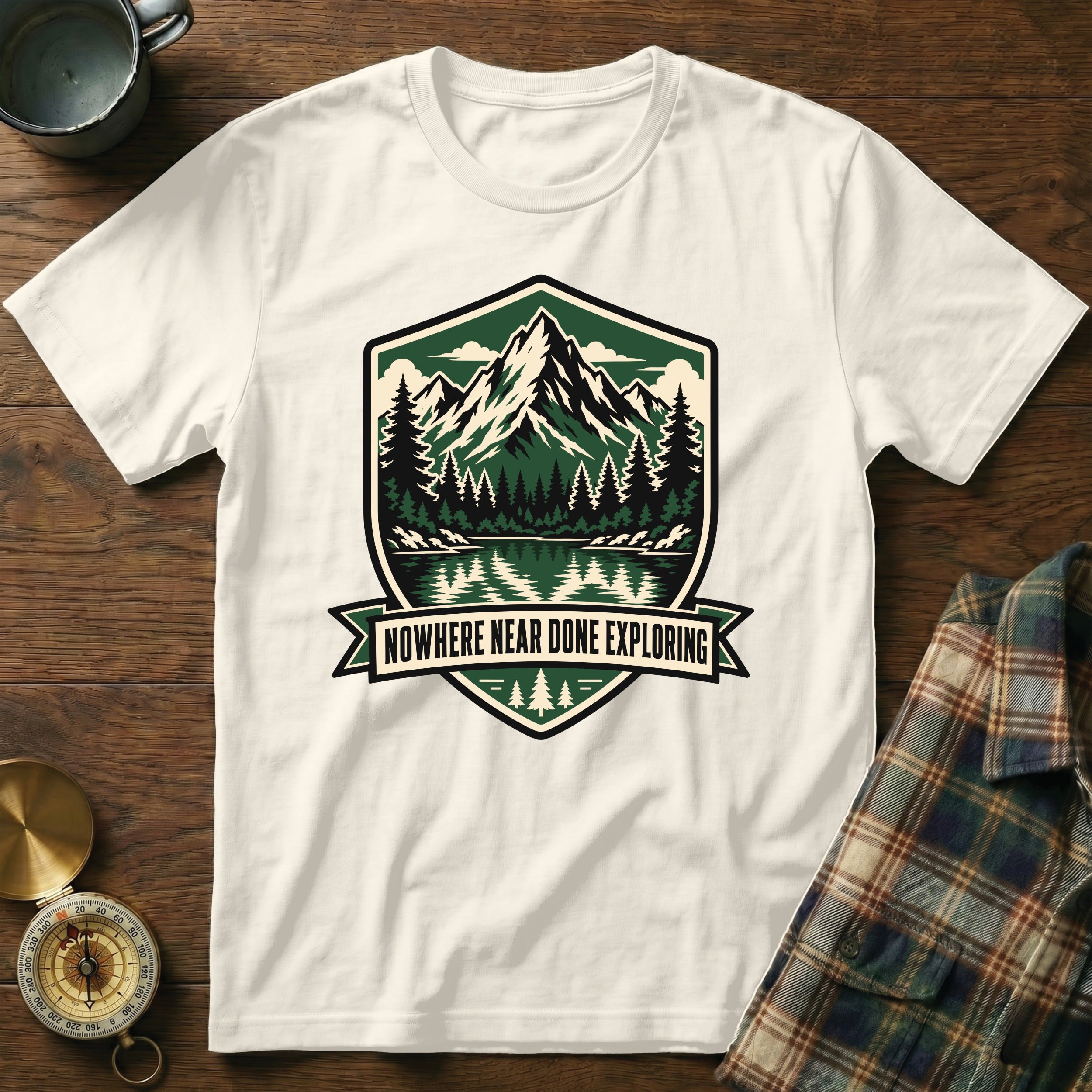 White t-shirt with mountain lake graphic and "Nowhere Near Done Exploring" text.