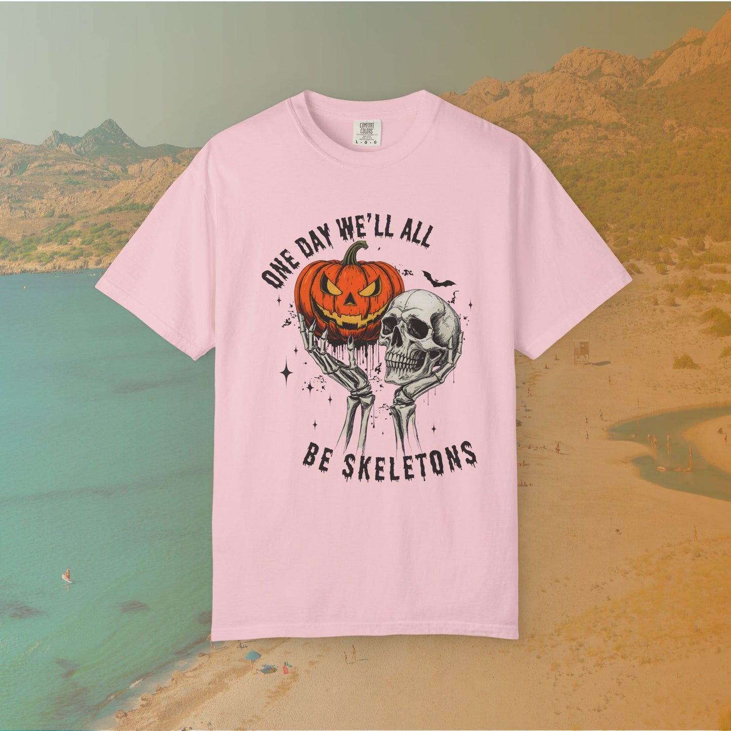 Skeleton hands holding a jack-o'-lantern and skull with the phrase ‘One Day We’ll All Be Skeletons’ in grunge font