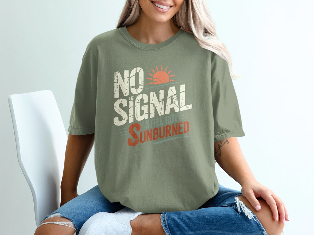 Olive green t-shirt with "NO SIGNAL STILL GOT SUNBURNED" graphic and sun design.