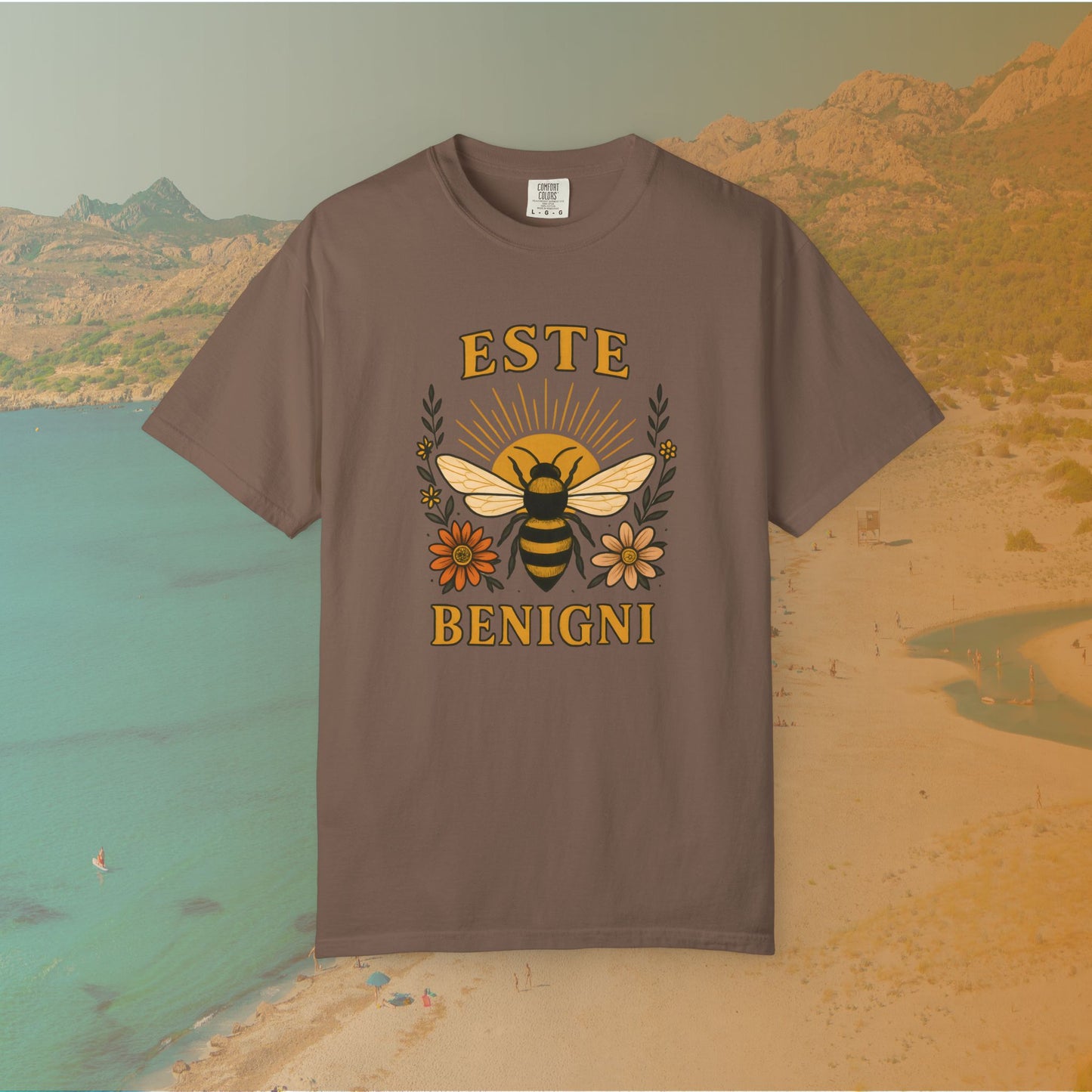 brown t-shirt Vintage-style graphic tee featuring a large, central honey bee with sunburst wings, flanked by retro flowers. The Latin words "ESTE BENIGNI" for "BEE KIND" are printed above and below the design.