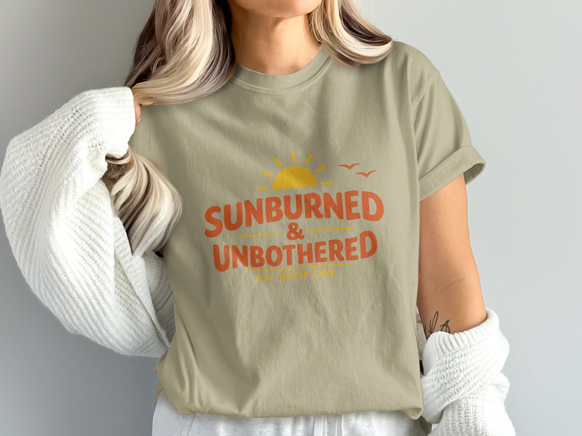 Tan t-shirt with orange text "SUNBURNED & UN<bos>BOTHERED" and a sun graphic.