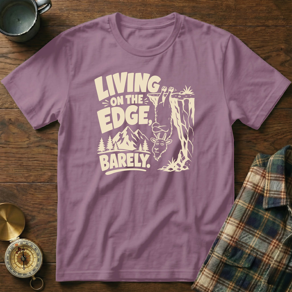 Purple t-shirt with a goat hanging off a cliff saying "Living on the Edge, Barely."