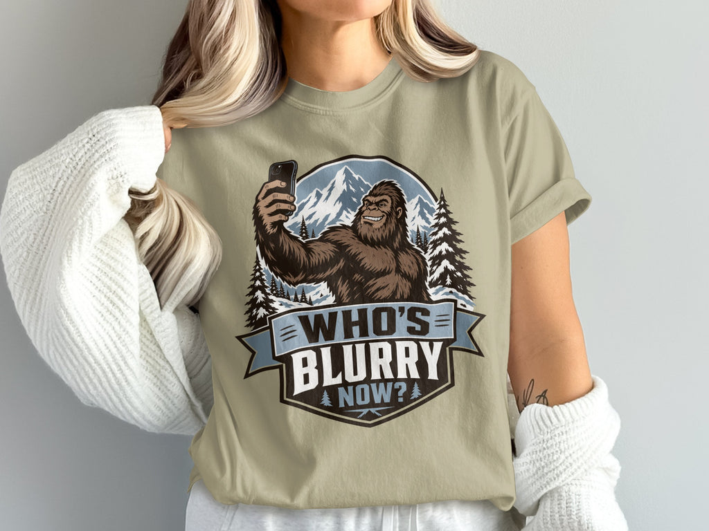 Bigfoot taking a selfie with mountains and trees, text reads "WHO'S BLURRY NOW?"