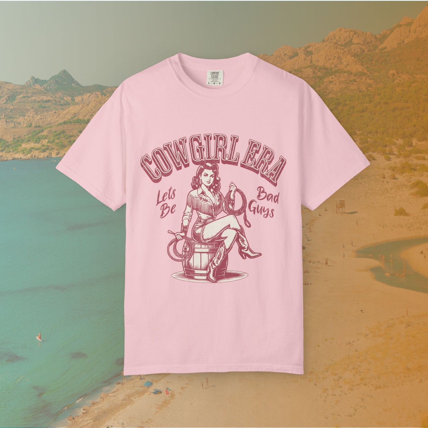 Cowgirl Era pinup T-shirt with a vintage-style illustration of a sassy cowgirl sitting on a barrel holding a lasso. The graphic includes the text "COWGIRL ERA" and "Lets Be Bad Guys.