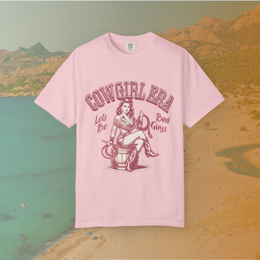 Cowgirl Era pinup T-shirt with a vintage-style illustration of a sassy cowgirl sitting on a barrel holding a lasso. The graphic includes the text "COWGIRL ERA" and "Lets Be Bad Guys.