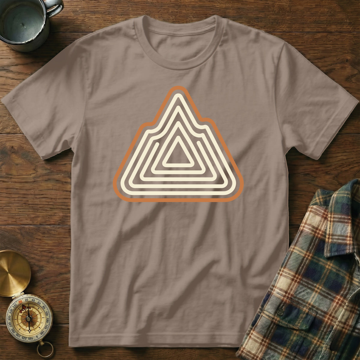 Brown t-shirt with abstract mountain range design in cream and orange.