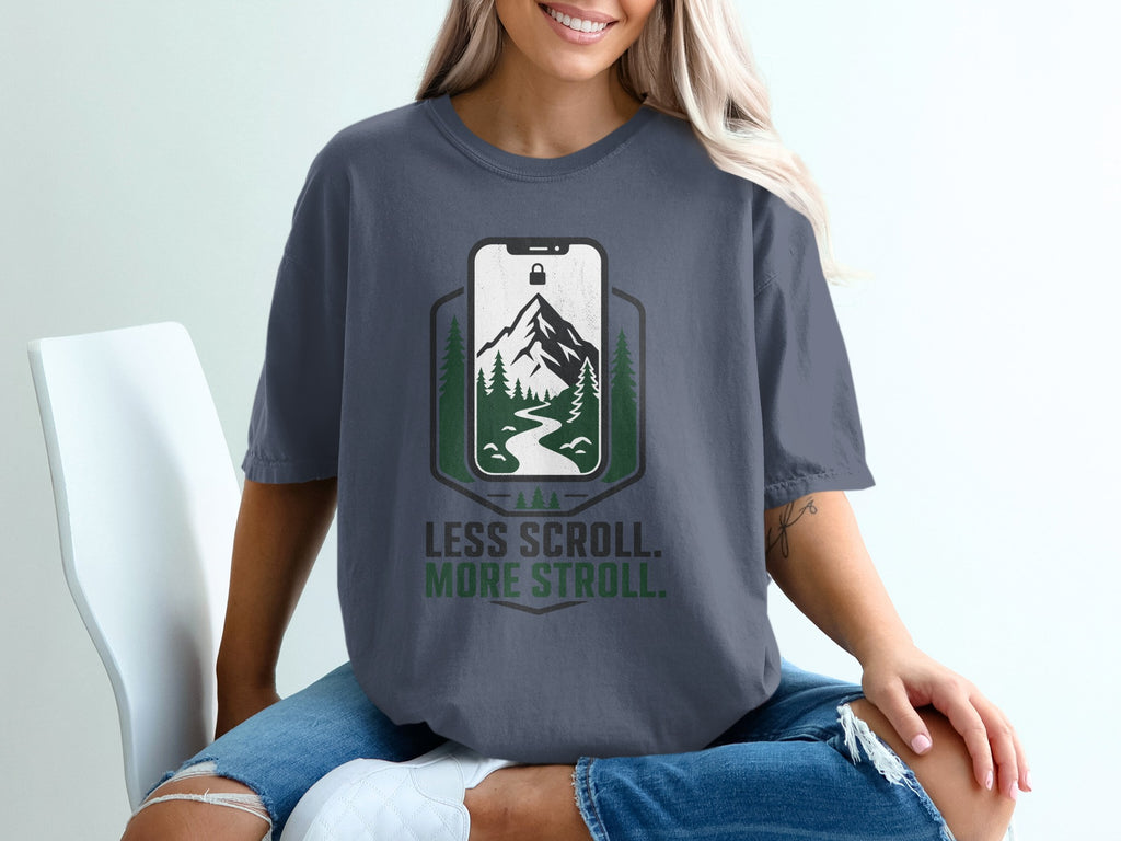 T-shirt with "Less Scroll. More Stroll." text and mountain landscape on phone screen.