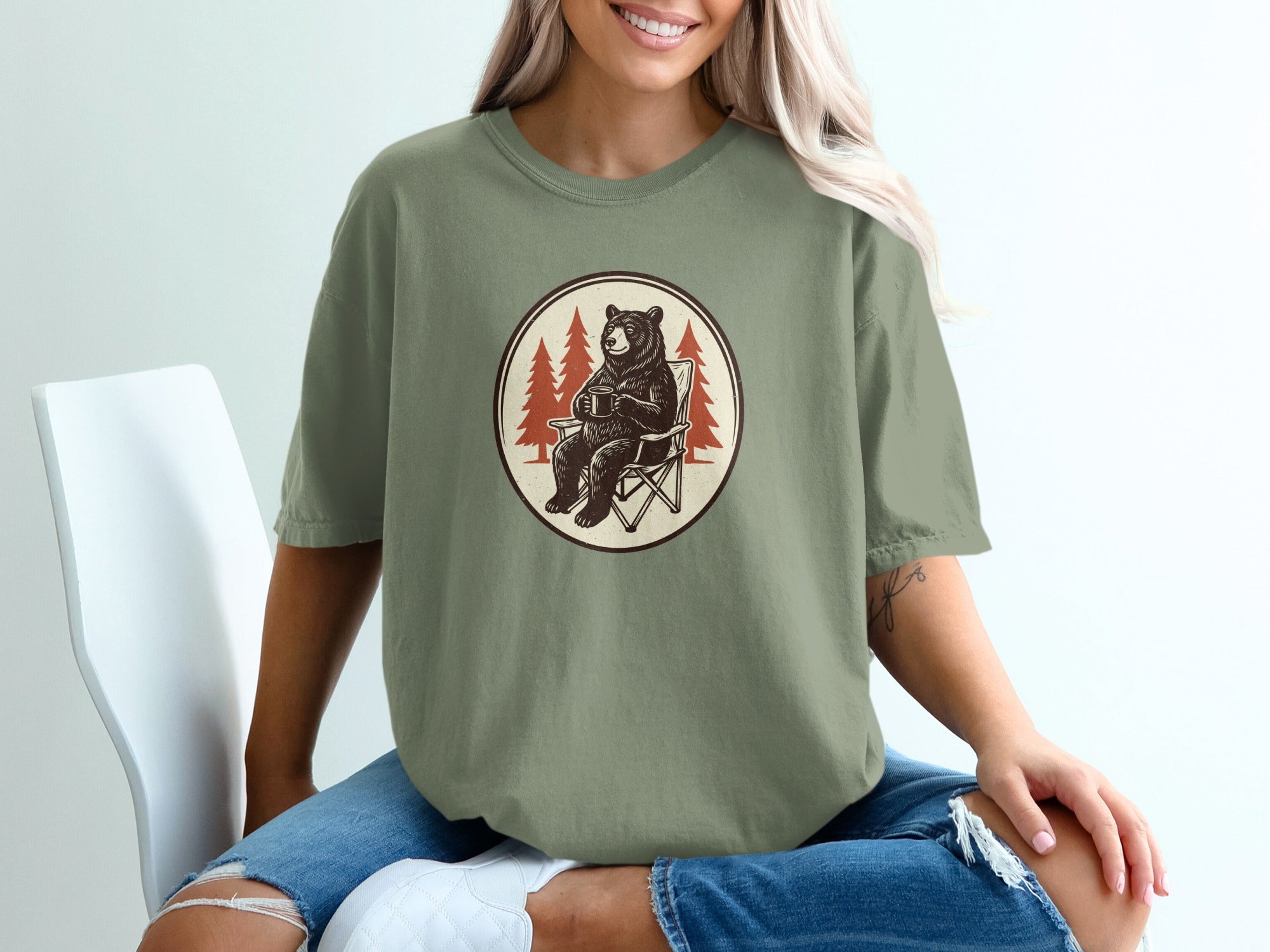 Illustration of a bear sitting in a camping chair holding a mug, with pine trees.