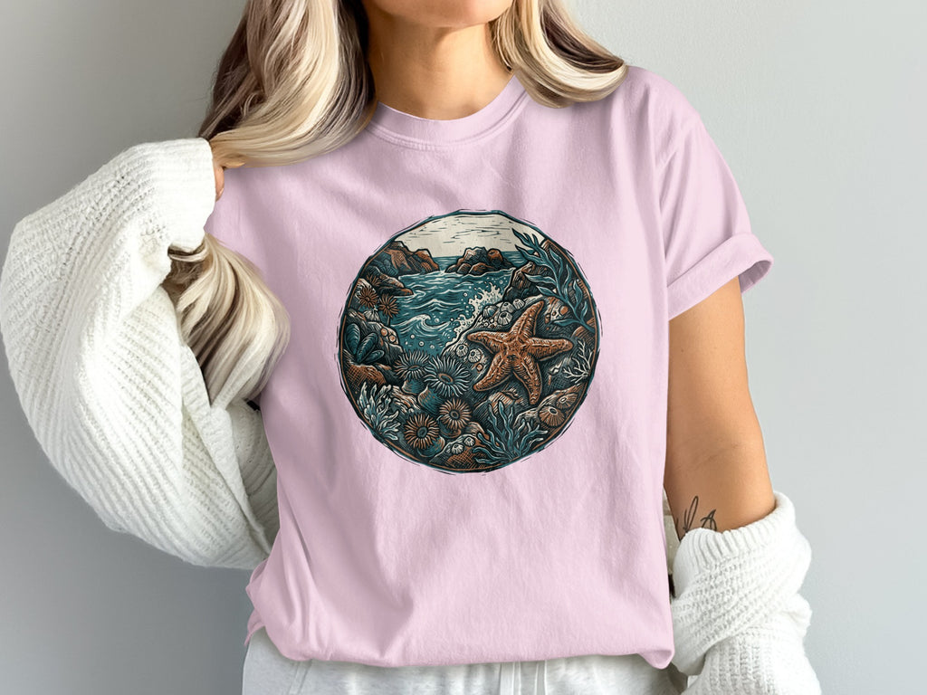 Pink t-shirt with circular ocean scene featuring starfish and seaweed.