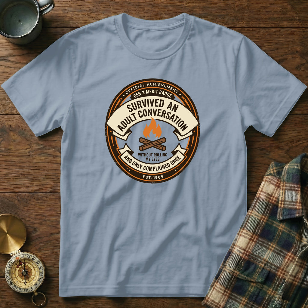 Light blue t-shirt with a circular badge for "Survived an Adult Conversation" merit badge.