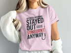Pink t-shirt with "Hooked Nothing Stayed Sunburnt Anyway" and fishing hook graphic.