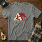Gray t-shirt with running person and bear graphic, plaid shirt and compass nearby.