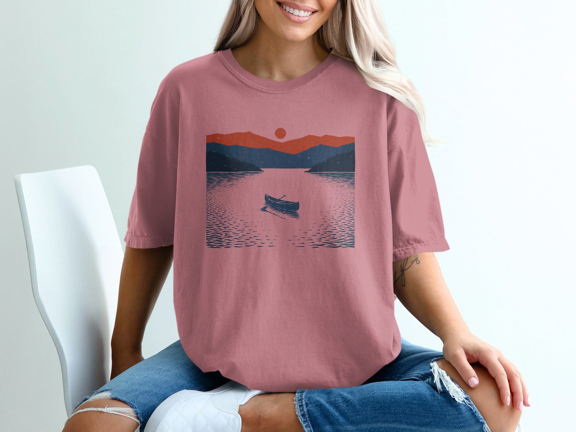 T-shirt with a sunset mountain landscape print and a canoe on water.