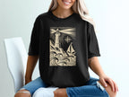 Black t-shirt with a cream lighthouse, waves, and sailboat design.